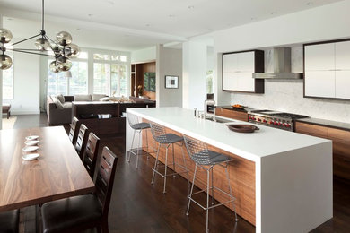 Open concept kitchen - contemporary l-shaped open concept kitchen idea in Minneapolis with an undermount sink, flat-panel cabinets, solid surface countertops, white backsplash, stone slab backsplash, stainless steel appliances and white cabinets