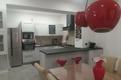 Immagine di una cucina contemporanea con lavello da incasso, ante in legno chiaro, top in laminato, pavimento in gres porcellanato, penisola e top grigio
