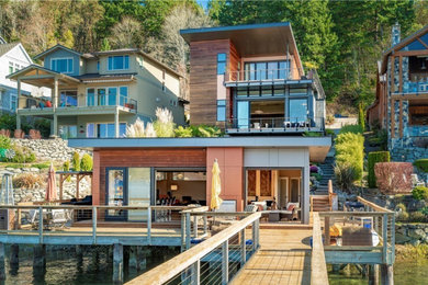 Example of a two-story wood house exterior design in Seattle with a butterfly roof and a metal roof