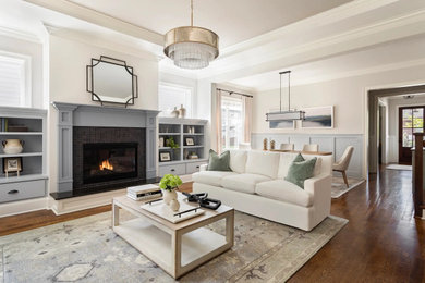 Inspiration for a mid-sized transitional open concept medium tone wood floor and tray ceiling living room remodel in Nashville with beige walls, a standard fireplace and a tile fireplace