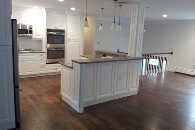 Large traditional l-shaped eat-in kitchen in New York with an undermount sink, raised-panel cabinets, white cabinets, granite benchtops, stainless steel appliances, medium hardwood floors and with island.