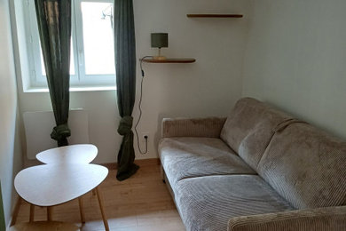 Inspiration pour un salon minimaliste de taille moyenne et fermé avec un mur blanc, sol en stratifié, aucune cheminée, aucun téléviseur et un sol marron.