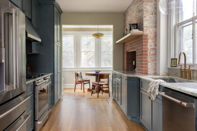 Inspiration for a mid-sized transitional galley medium tone wood floor and brown floor eat-in kitchen remodel in Baltimore with an undermount sink, recessed-panel cabinets, green cabinets, granite countertops, green backsplash, glass tile backsplash, stainless steel appliances, an island and green countertops