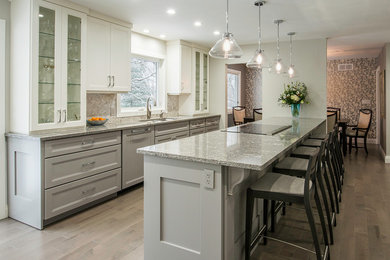 Mid-sized transitional medium tone wood floor open concept kitchen photo in Toronto with an undermount sink, gray cabinets, quartzite countertops, gray backsplash, mosaic tile backsplash, paneled appliances, a peninsula and shaker cabinets