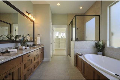 Inspiration for a mid-sized transitional master bathroom in Austin with recessed-panel cabinets, medium wood cabinets, granite benchtops, beige tile, porcelain tile, a drop-in tub, an undermount sink, green walls and porcelain floors.