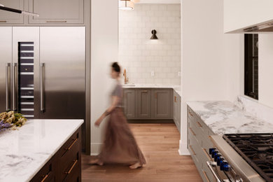 リッチモンドにあるラグジュアリーなモダンスタイルのおしゃれなキッチン (シルバーの調理設備、淡色無垢フローリング、茶色い床、大理石カウンター、白いキッチンパネル、大理石のキッチンパネル、白いキッチンカウンター) の写真