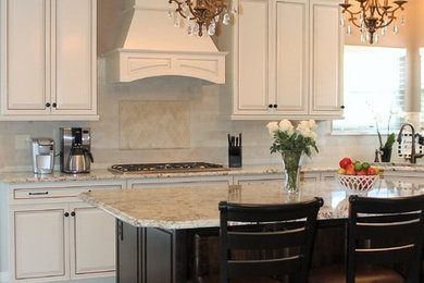 Inspiration for a large timeless l-shaped medium tone wood floor eat-in kitchen remodel in St Louis with an undermount sink, raised-panel cabinets, beige cabinets, granite countertops, beige backsplash, stone tile backsplash, stainless steel appliances and an island