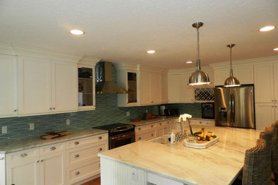 Example of a large classic l-shaped medium tone wood floor and brown floor kitchen design in Miami with a farmhouse sink, shaker cabinets, white cabinets, blue backsplash, stainless steel appliances, an island and ceramic backsplash