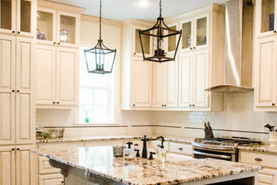 Example of a mid-sized country l-shaped dark wood floor and brown floor kitchen design in Austin with a farmhouse sink, raised-panel cabinets, beige cabinets, granite countertops, white backsplash, subway tile backsplash, stainless steel appliances and an island