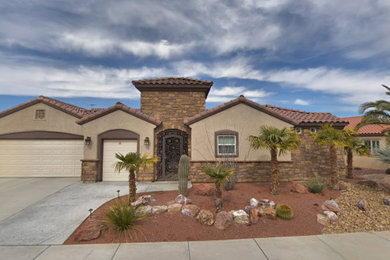 Large southwest beige two-story brick house exterior photo in Las Vegas with a hip roof, a tile roof and a brown roof
