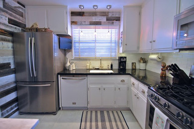 This is an example of a small contemporary l-shaped separate kitchen in Los Angeles with an undermount sink, raised-panel cabinets, white cabinets, granite benchtops, white splashback, subway tile splashback, stainless steel appliances, porcelain floors and no island.