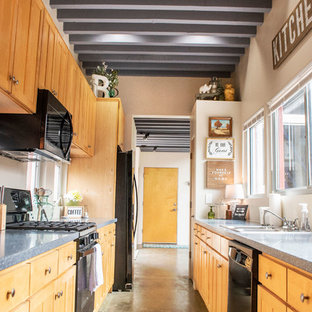 Modern inredning av ett stort blå blått kök, med en nedsänkt diskho, skåp i shakerstil, skåp i ljust trä, granitbänkskiva, svarta vitvaror, betonggolv och grönt golv