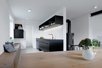 Offene, Einzeilige, Mittelgroße Moderne Küche ohne Insel mit flächenbündigen Schrankfronten, schwarzen Schränken, Küchenrückwand in Weiß und Betonboden in München