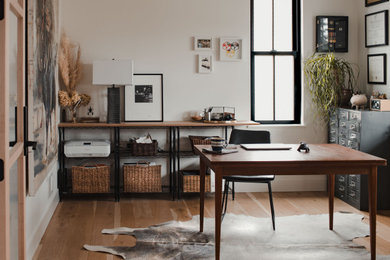 Diseño de despacho bohemio de tamaño medio sin chimenea con paredes blancas, suelo de madera clara y escritorio independiente