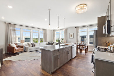 Mid-sized transitional galley dark wood floor and brown floor open concept kitchen photo in New York with an undermount sink, shaker cabinets, brown cabinets, quartzite countertops, white backsplash, subway tile backsplash, stainless steel appliances, an island and white countertops