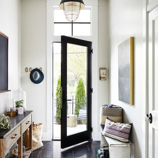 ワシントンD.C.の片開きドアビーチスタイルのおしゃれな玄関ホール (ベージュの壁、ガラスドア、黒い床) の写真