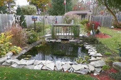 Photo of a mid-sized full sun backyard pond in Calgary.