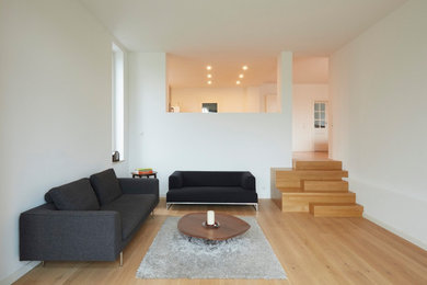 Mittelgroßes, Fernseherloses, Offenes Modernes Wohnzimmer ohne Kamin mit weißer Wandfarbe und hellem Holzboden in Dortmund