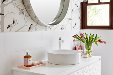 Inspiration for a mid-sized contemporary powder room in Sydney with furniture-like cabinets, white cabinets, a one-piece toilet, white tile, ceramic tile, porcelain floors, a vessel sink, engineered quartz benchtops, grey floor, white benchtops, a floating vanity and wallpaper.