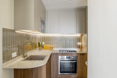 Imagen de cocinas en L beige y blanca mediterránea pequeña abierta y de nogal sin isla con fregadero sobremueble, armarios con paneles lisos, puertas de armario beige, encimera de cuarzo compacto, salpicadero gris, salpicadero de azulejos de cerámica, electrodomésticos de acero inoxidable, suelo de madera en tonos medios, suelo marrón y encimeras beige