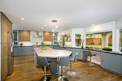 Inspiration for a large transitional u-shaped medium tone wood floor and brown floor eat-in kitchen remodel in San Diego with an undermount sink, shaker cabinets, gray cabinets, quartzite countertops, white backsplash, subway tile backsplash, stainless steel appliances and an island