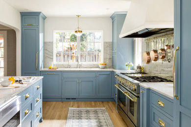 Inspiration for a mid-sized transitional galley light wood floor eat-in kitchen remodel in Portland with an undermount sink, recessed-panel cabinets, blue cabinets, quartzite countertops, stone slab backsplash, paneled appliances and a peninsula