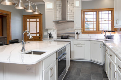 Minimalist l-shaped gray floor kitchen photo in Chicago with shaker cabinets, white cabinets, quartzite countertops, white backsplash, ceramic backsplash, stainless steel appliances, an island and white countertops
