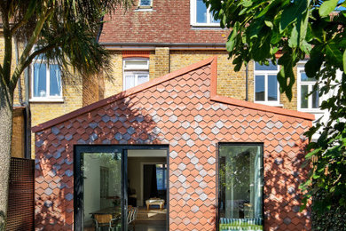 Inspiration for a red contemporary clay and front house exterior in London with a pitched roof and a red roof.