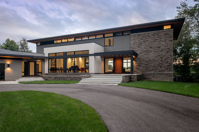 Example of a large minimalist gray two-story concrete fiberboard house exterior design in Other with a hip roof and a shingle roof