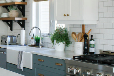 Inspiration for a mid-sized cottage l-shaped light wood floor and brown floor open concept kitchen remodel in Toronto with a farmhouse sink, shaker cabinets, green cabinets, quartz countertops, white backsplash, subway tile backsplash, stainless steel appliances, an island and white countertops