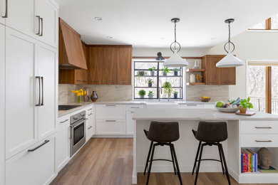 Mid-sized transitional l-shaped vinyl floor and brown floor eat-in kitchen photo in Minneapolis with a farmhouse sink, flat-panel cabinets, white cabinets, quartzite countertops, gray backsplash, stone slab backsplash, paneled appliances, an island and gray countertops