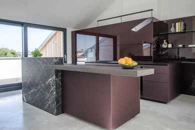 This is an example of an expansive contemporary galley eat-in kitchen in Berlin with a single-bowl sink, glass-front cabinets, purple cabinets, glass benchtops, glass sheet splashback, black appliances, concrete floors, with island, grey floor and purple benchtop.