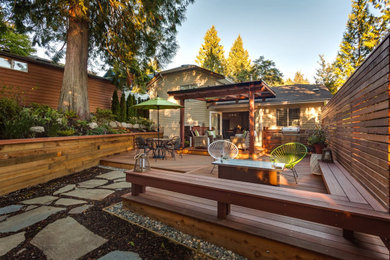 Mid-sized elegant backyard privacy deck photo in Calgary with a pergola