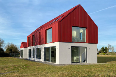 Ejemplo de fachada de casa roja y roja minimalista grande de dos plantas con revestimiento de metal, tejado a dos aguas y tejado de metal