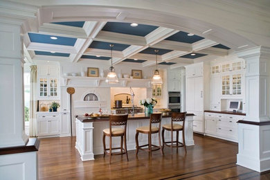 Inspiration for a large traditional u-shaped eat-in kitchen in Boston with raised-panel cabinets, white cabinets, wood benchtops, white splashback, stainless steel appliances, medium hardwood floors, with island, a double-bowl sink and ceramic splashback.