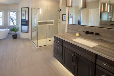 This is an example of an expansive transitional master bathroom in Other with shaker cabinets, dark wood cabinets, a freestanding tub, a corner shower, a one-piece toilet, gray tile, ceramic tile, ceramic floors, an undermount sink, quartzite benchtops, grey floor, a hinged shower door, grey benchtops, an enclosed toilet, a double vanity and a floating vanity.