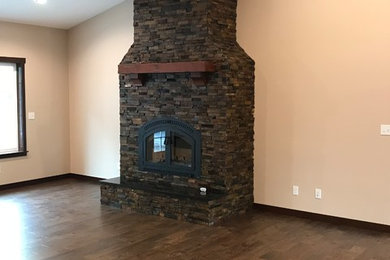 Living room - traditional open concept medium tone wood floor and brown floor living room idea in Seattle with beige walls, a wood stove and a stone fireplace