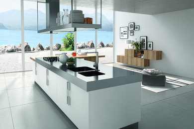 Inspiration for a large contemporary single-wall linoleum floor open concept kitchen remodel in Santa Barbara with a double-bowl sink, flat-panel cabinets, white cabinets, solid surface countertops, stainless steel appliances and an island