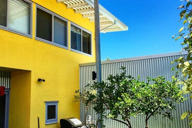 Photo of a mid-sized contemporary two-storey yellow exterior in Perth with metal siding and a flat roof.