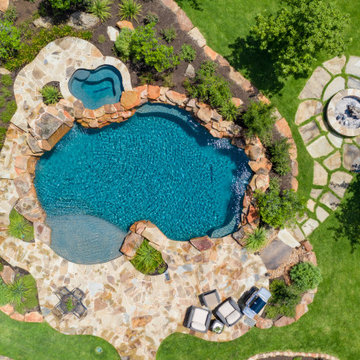 Freeform pool with weeping wall, grotto, and spa in San Antonio, Tx