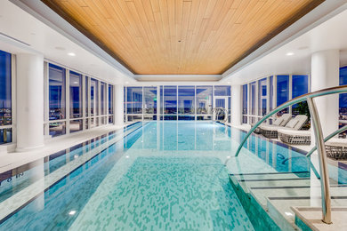 This is an example of a large contemporary indoor rectangular infinity pool in Baltimore with tile.