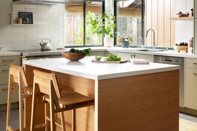 Example of a mid-sized trendy l-shaped porcelain tile and gray floor kitchen pantry design in Sacramento with an undermount sink, flat-panel cabinets, green cabinets, quartz countertops, gray backsplash, porcelain backsplash, stainless steel appliances, an island and white countertops