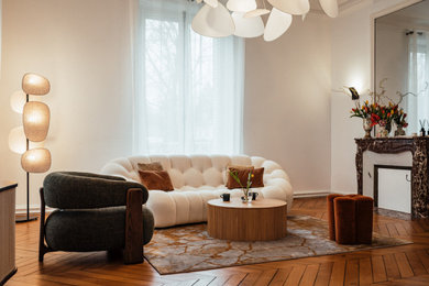 Réalisation d'un grand salon blanc et bois tradition ouvert et haussmannien avec une bibliothèque ou un coin lecture, un mur blanc, parquet clair, une cheminée standard, un manteau de cheminée en pierre, un téléviseur dissimulé, un sol beige, un plafond en bois et boiseries.