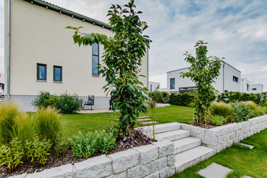 Gartenanlage mit bepflanzter  Sockelmauer und Blockstufen aus Granit