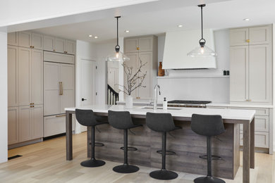 This is an example of a medium sized rural u-shaped open plan kitchen in Toronto with a submerged sink, shaker cabinets, beige cabinets, engineered stone countertops, white splashback, engineered quartz splashback, integrated appliances, light hardwood flooring, an island, yellow floors and white worktops.