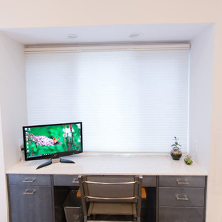 Medium sized modern home office and library in Boston with white walls, slate flooring, a built-in desk and black floors.