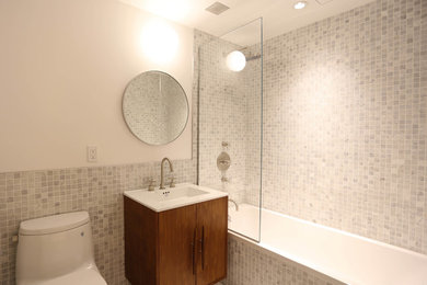 Midcentury bathroom in New York with gray tile, marble, marble floors and grey floor.