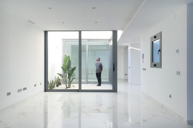 Diseño de salón abierto mediterráneo de tamaño medio con paredes blancas, suelo de baldosas de cerámica y suelo blanco