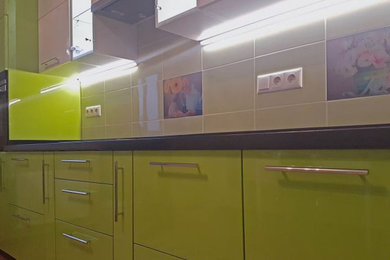 На фото: отдельная, прямая кухня среднего размера в современном стиле с врезной мойкой, плоскими фасадами, зелеными фасадами, столешницей из ламината и черной столешницей без острова с