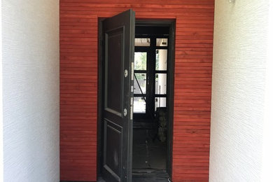 他の地域にある高級な小さなモダンスタイルのおしゃれな玄関ドア (磁器タイルの床、黒い床、赤い壁、黒いドア) の写真